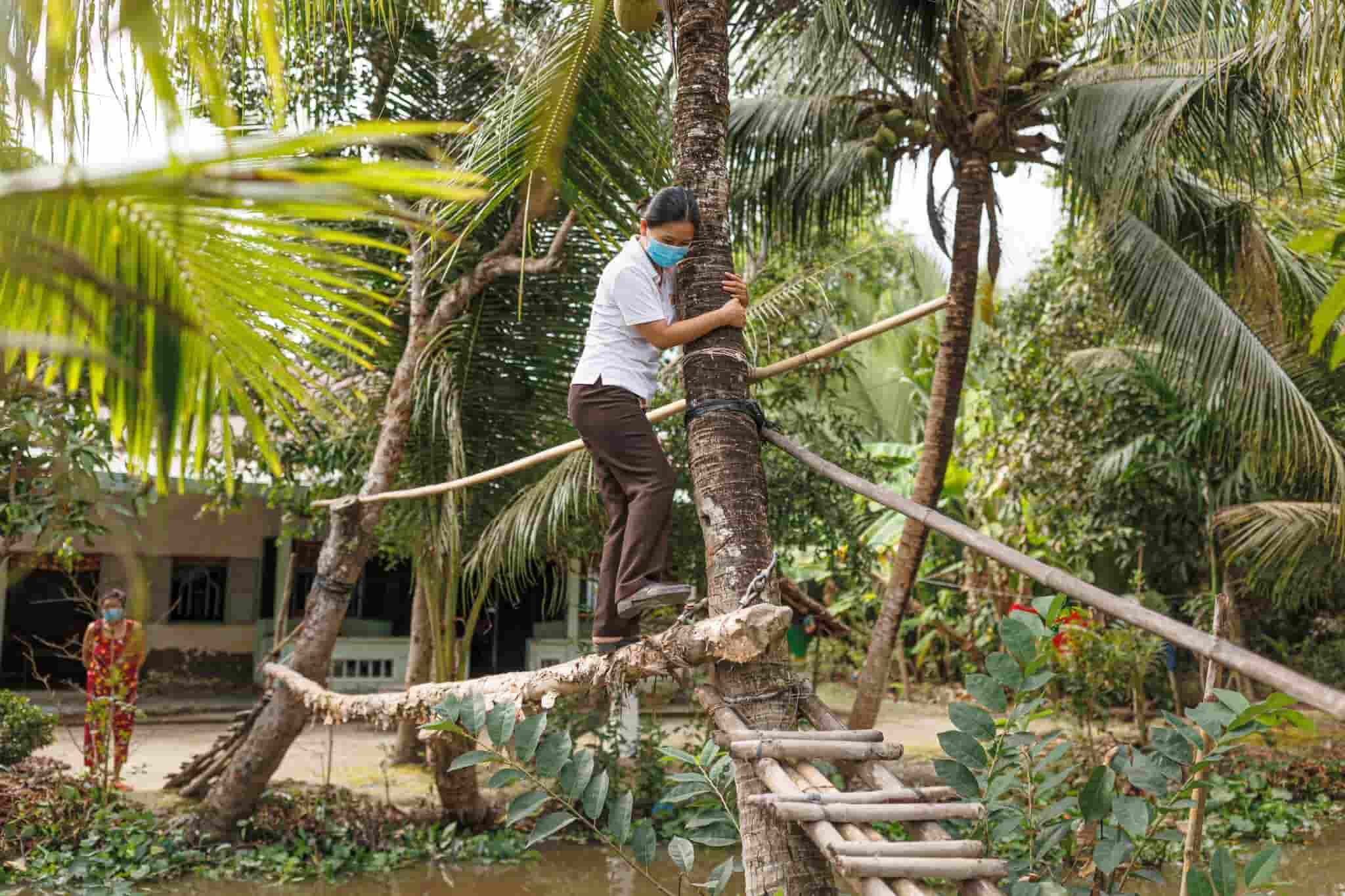 Ánh Dương centre social worker Lê Thế Quyên attempts to cross a ‘monkey bridge’, which are simple wood or bamboo walkways built across streams, sometimes without handrails. Photo by Mervin Lee