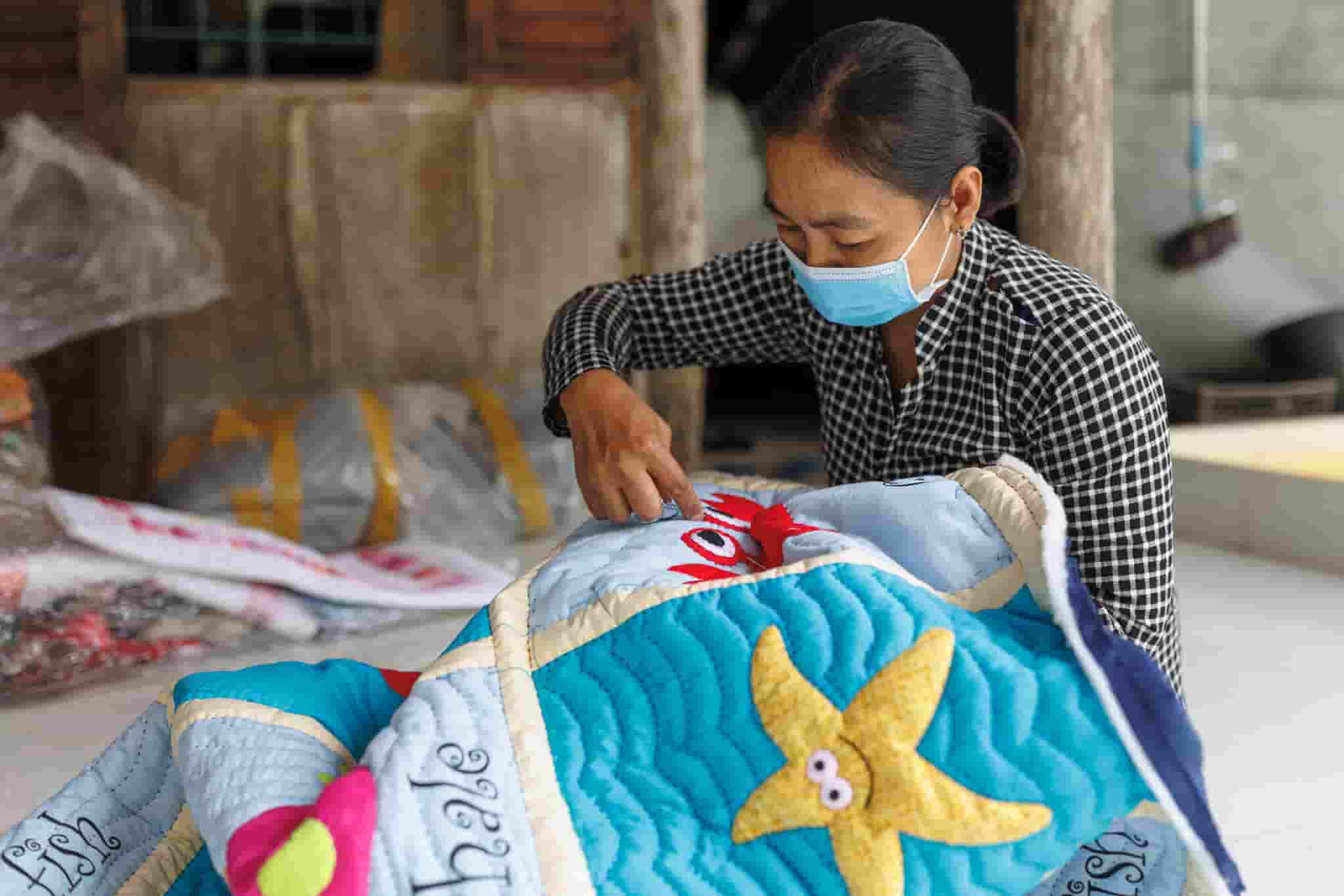 A craftswoman works on a quilt for Mekong Quilts in her home. Photo by Mervin Lee