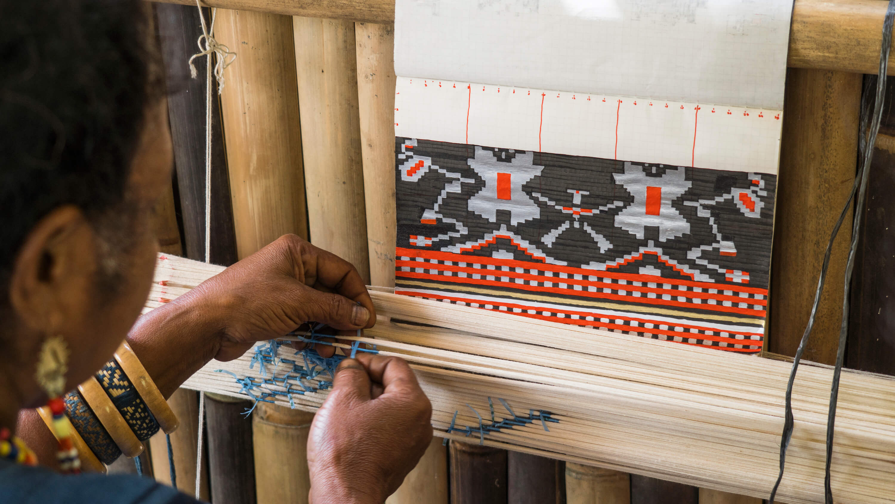 A weaver from Watubo demonstrates resist-binding, a process of binding the yarn to create the desired motif. Photo by Andra Fembriarto