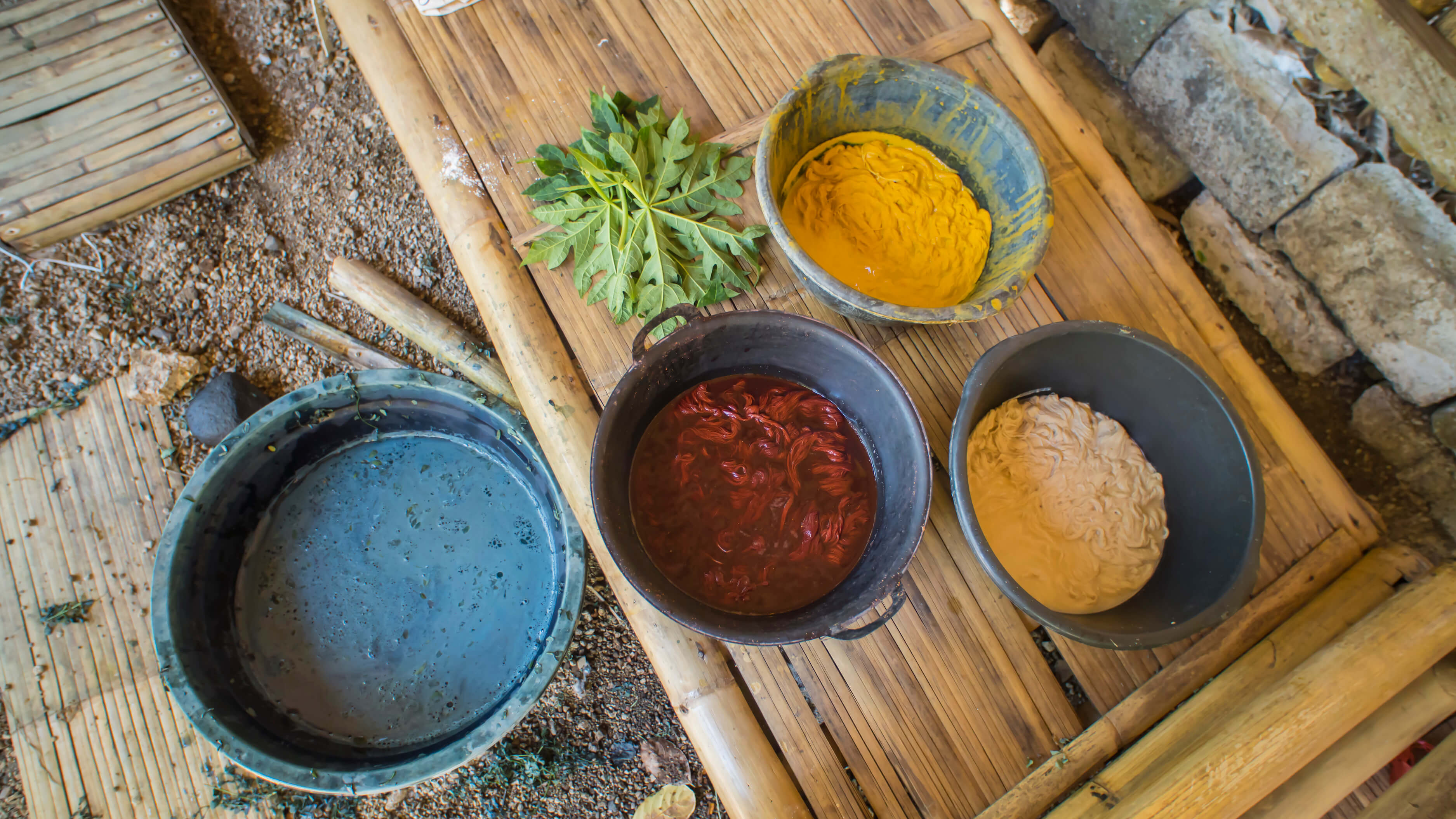 Bowls of colourful dye derived naturally from plants, such as tumeric (yellow), indigo and morinda roots (red). Photo by Andra Fembriarto